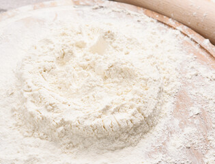 white wheat flour heaped on a round wooden board