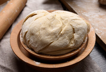 Fototapeta na wymiar kneaded dough made of white wheat flour in a wooden plate
