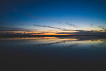 Fototapeta premium 波の水たまりに反射した夕日と空と雲