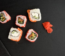 california sushi with red tobiko caviar and slices of philadelphia sushi on black slate board