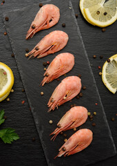 fresh shrimp in a row on a black slate board