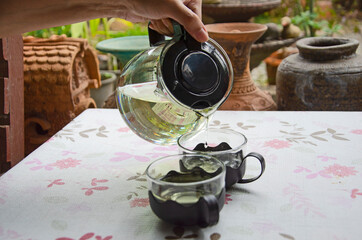 Tea pouring from teapot into cups on the table