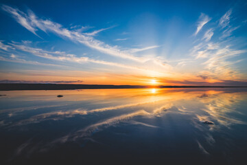 波の水たまりに反射した夕日と空と雲