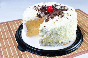 Cake decorated with vanilla and arequipe on white plate and light colored wooden background