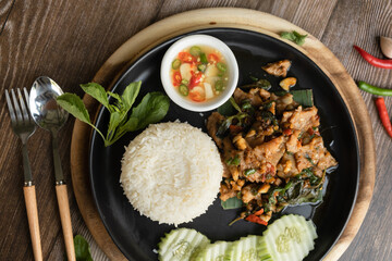 Rice topped with stir-fried pork and basil ready to eat, close up, wooden back ground
