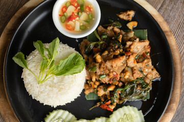 Rice topped with stir-fried pork and basil ready to eat, close up, wooden back ground