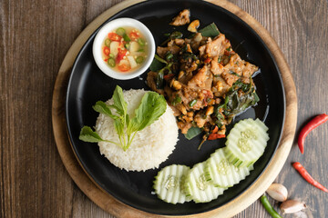 Rice topped with stir-fried pork and basil ready to eat, close up, wooden back ground