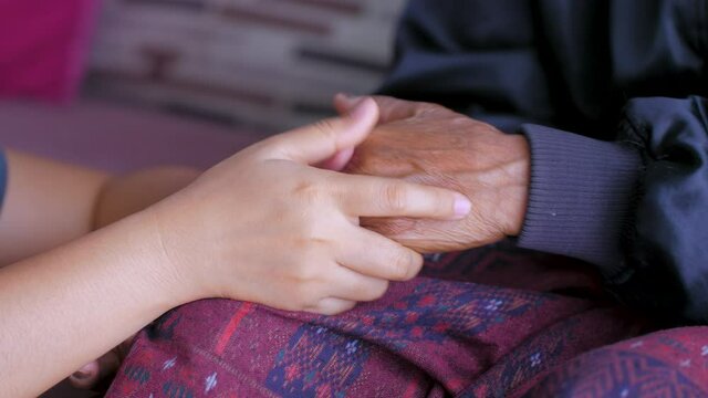 Hands of a young woman softly touching to hands of the old woman for consolation and encourage, for family and difference age, selective focus shallow depth of field