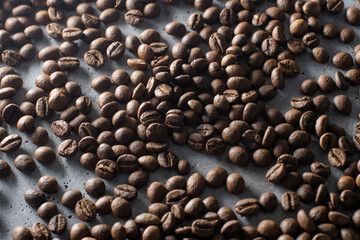 Brown roasted coffee beans falling on pile. Represent breakfast, energy, freshness or great aroma,Flying on dark background with copy space, close-up