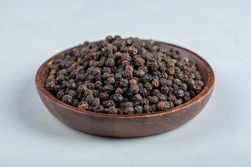 A wooden plate full of dried pepper on a white background