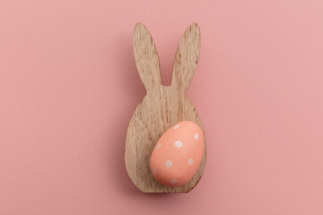 Minimal easter holiday background. Wooden easter bunny and egg on pink