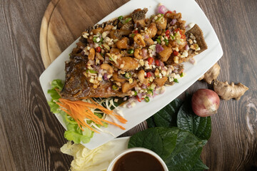 Fried fish served with fresh vegetable and special sauce ready to eat, wooden background