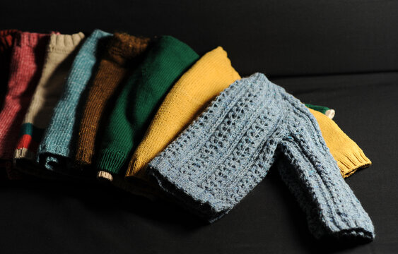 multicolored handmade knitted items on a black background