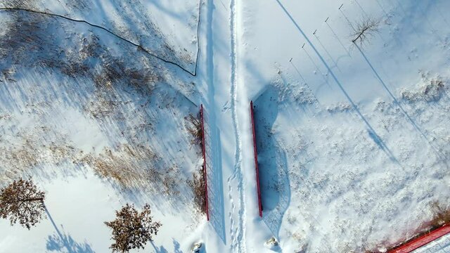 overhead aerial drone view of a walkway in a snowy park after a winter storm in Chicago. the environment is covered cold icy snow during a nice sunny day 