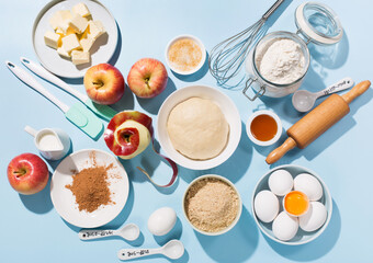 Cooking baking background with ingredients, fresh apples, spices and utensils on blue table.