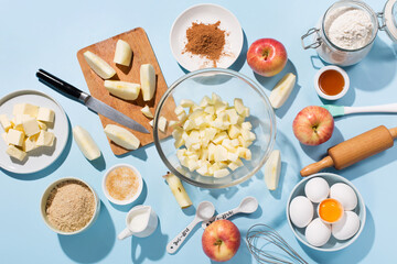 Cooking baking background with ingredients, fresh apples, spices and utensils on blue table.