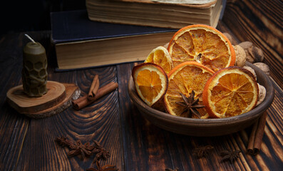  plate with dried orange slices on a dark wooden table next to a candle made of natural handmade wax. selective focus. 