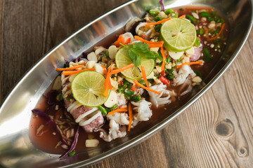 Steam Squid with Spicy Chili and Lemon Sauce - Pla Muk Nung Manow on wooden background ready to eat