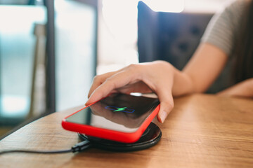 Charging mobile phone battery with wireless charging device in the table. Smartphone charging on a charging pad. Mobile phone near wireless charger Modern lifestyle concept.