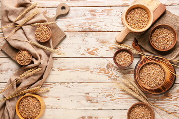 Bowls with wheat grains on light wooden background