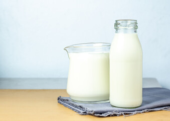 Pure milk drinks in clear jars and bottles are naturally healthy foods placed on a gray cloth on a blue background.