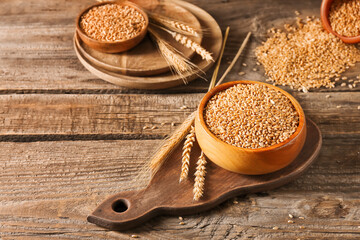 Bowl with wheat grains on wooden background