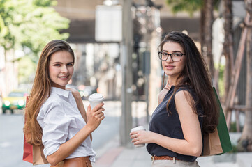 Young shopaholic friends women friends walking and carry shopping bags in the street city with happy and smiling.