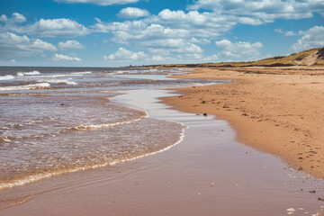 Waves lap up on a sandy beach on the north shore of Prince Edward Island, Canada.