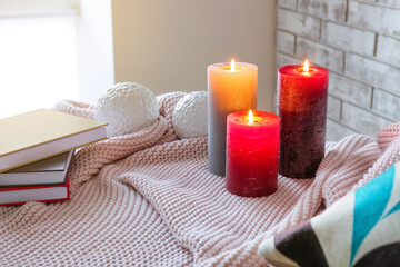 Burning candles on plaid in room