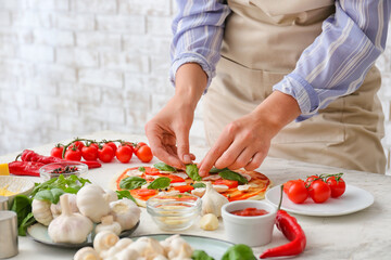 Woman making pizza on table in kitchen