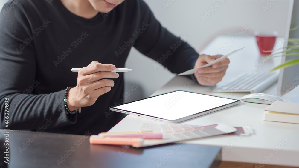 Poster close up of a man designer hand selecting a color scheme and using the tablet at the office.