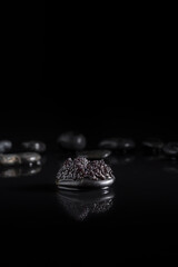 Caviar de esturión sobre piedra negra con reflejo en un fondo negro