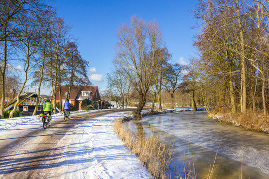 People riding their bicycle on a snow covered road in Groningen, Netherlands