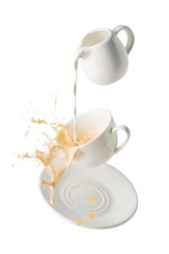 pouring milk and splashing milk tea from flying cup and saucer isolated on white background