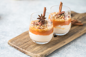 Autumn trifle dessert. Layered pumpkin parfait , pecan nut dessert in a glass, with autumn decorations.