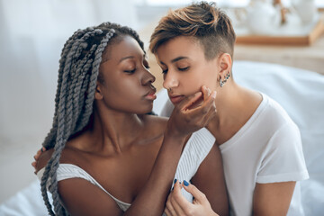 Same-sex couple sitting close to each other looking tender and passionate