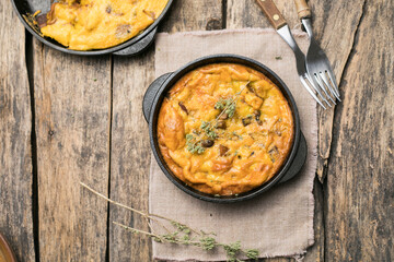 Frittata with mushrooms in a pan on wooden background. Fritata is an Italian breakfast dish.