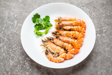 A dish of boiled black tiger prawns on cement shading