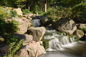 Fototapeta na wymiar peaceful flowing stream small waterfall Holland park London