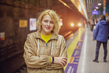 Young European woman is waiting for train on subway station platform.