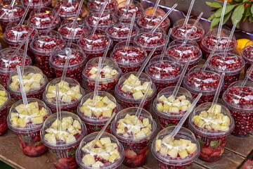 Fruit desserts in plastic cups are on shop counter.