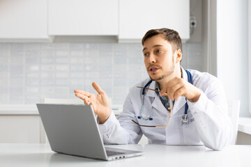 Doctor during an online video call in front of a laptop monitor. He communicates with the patient and gives advice on treatment.