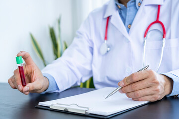 The doctor was holding a tube of infected blood samples to take notes and analyze. A sample of the patient's blood At the table in the office, the concept of analyzing infected blood. coronavirus19