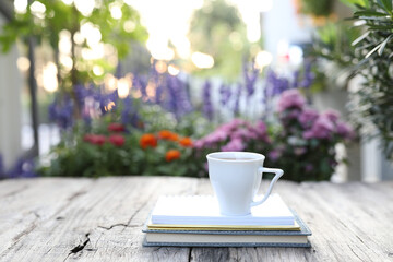 coffee cup and notebooks on wooden table with flowers