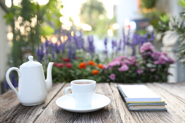 coffee cup and kettle and notebooks on wooden table with flowers