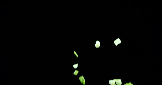 Fresh green onion leaves slowly fly up and fall on a black background. Blackmagic Ursa Pro G2, 300 fps.