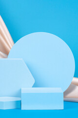 Geometric podium on light blue background with draped champagne color silk cloth. Empty showcase...
