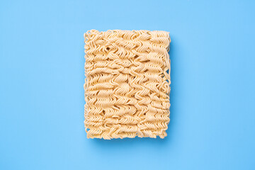 Instant noodles on blue background, top view