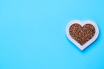 Buckwheat in the shape of a heart on a blue background. Silver heart. Copy-space