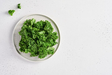 Bowl of fresh green chopped kale on light gray stone background, top view. Ingredient for making healthy salad. Clean eating, detox or diet concept. Mock up.